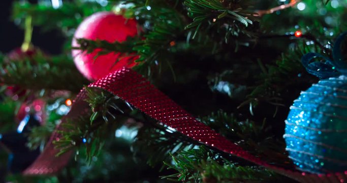 Christmas Tree Decorations. Christmas tree branches decorated with bright sparkling garlands and Christmas decorations are slowly moving in front of the camera