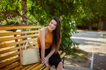 female student, a young girl with a bag smiling, resting on a park bench.