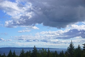Fototapeta na wymiar Fundy National Park, New Brunswick, Canada: Bright blue sky with fluffy white clouds over the Bay of Fundy at high tide.