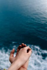 Two hands against of blue ocean. From above