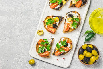 Olives cherry tomatoes goat cheese bruschetta. Top view, space for text.