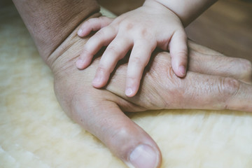 baby's hands on grandfather's hand