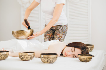 Girl doing massage therapy singing bowls in the Spa