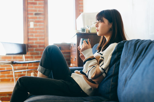 Woman sitting on sofa with cup of tea