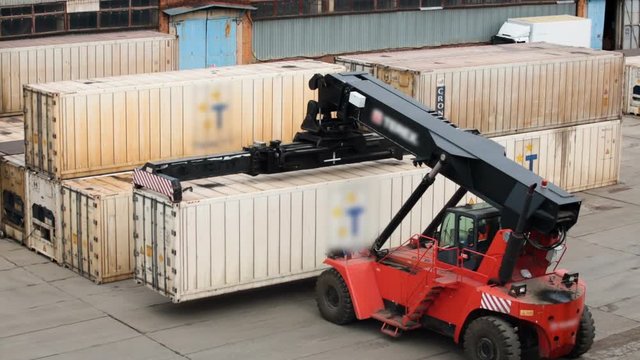 Metal containers stand on top of each other. Excavator lifts container quadcopter view