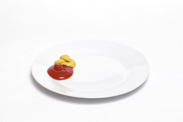 Ketchup and mustard on a white dish against white background