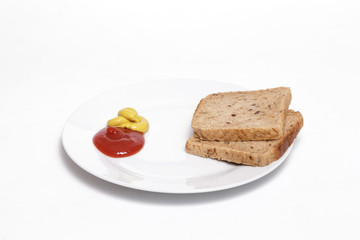 Ketchup, mustard and full grain bread slices on a white dish against white background