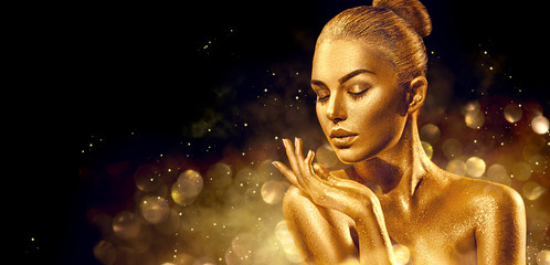 Christmas woman. Golden skin woman portrait closeup. Sexy model girl with holiday golden shiny professional makeup. Golden metallic body