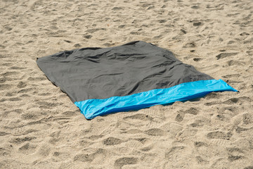 Waterproof and sandproof nylon beach blanket on sand. Very thin tarp or footprint used for outdoor activities, as a barrier agains the sand or ground, keeps you dry and clean.