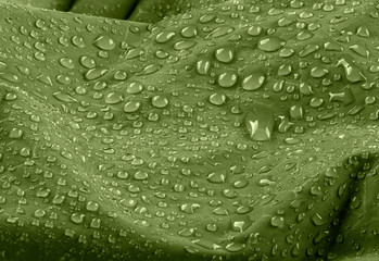 Water drops on waterproof green nylon fabric. Macro detail view of texture of woven synthetic...