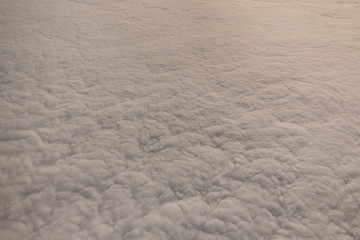 Layer of clouds taken from aircraft above scene illuminated by low evening or morning sun rays of warm golden color. Easy background photography of simple composition and empty space.