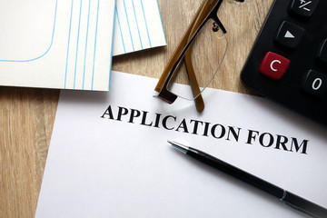 Application form with pen, calculator and glasses   on desk