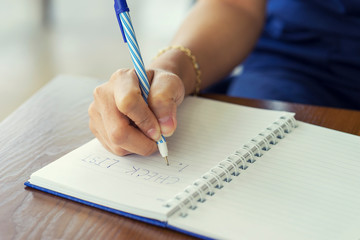 Woman hand writing check list on notebook, planning concept.