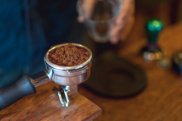 Espresso handle filled with ground coffee. Barista prepares espresso in his coffee shop.