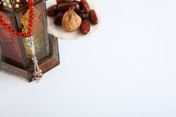 Muslim lamp, dates and prayer beads on white background. Space for text