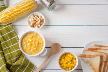 Corn soup in white bowl and crispy bread with corn on white table. Top view with Copy space.