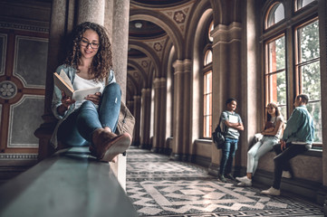 She loves reading.Beautiful female student sitting on the railing in the university and preparing...