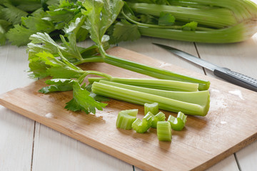 Fresh celery chopped on wooden cutting board.