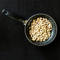 Frying pan with pistachios on a black background. Concept-cooking, menu, recipes.