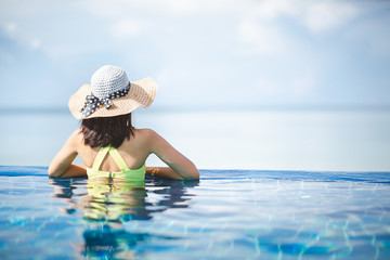 Asian woman relax in pool on beach