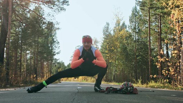 Training an athlete on the roller skaters. Biathlon ride on the roller skis with ski poles, in the helmet. Autumn workout. Roller sport. Adult man riding on skates. The athlete does the workout. Slow