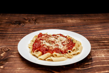 close in penne meal with red sauce and grated cheese, wooden background