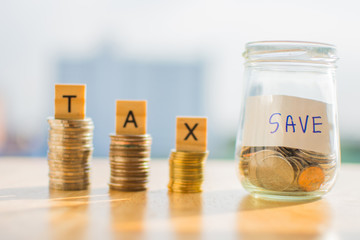 coin of money on wooden table and text TAX SAVE with blur background.
