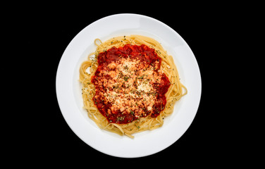 meal of noodles with red sauce and grated cheese on white plate, black background, top view