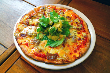 A pizza with tomato sauce, cheese and arugula salad on top