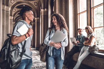 The best friends.Young smiling students standing in the university hall and speak with each other.