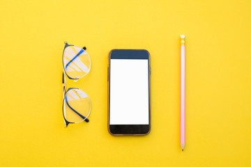 empty paper of notebook eyeglasses pencil and smart phone on yellow background