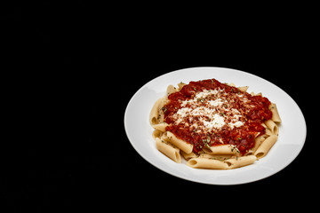 penne meal with red sauce and grated cheese, black background
