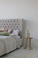 elegant bed with green and gild pillows at bedroom of the luxury apartment with white walls