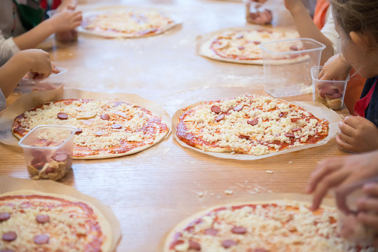 Children's hands make pizza - spread bacon on the base.