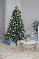 Elegant Christmas and New Year tree with gifts decorated for Christmas in luxury apartments with white walls