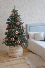Christmas tree with pink and gray paper toys in the bedroom with a soft blue bed  in the luxury apartments