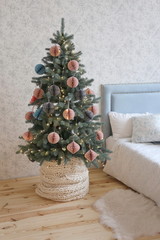 Christmas tree with pink and gray paper toys in the bedroom with a soft blue bed  in the luxury apartments