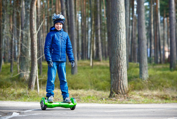 Happy boy riding on self-balancing deck in city park