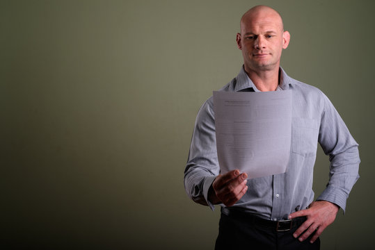 Portrait Of Bald Muscular Businessman Against Colored Background