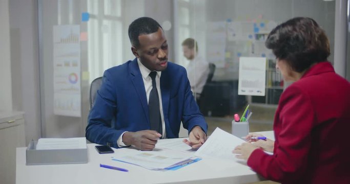 Image of african male bank assistant and his female client