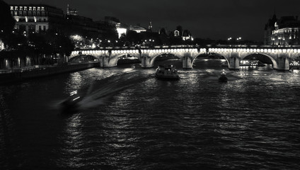 Night view of Seine river with Pont Neuf bridge, touristic ship and two police boats coming to the rescue. Paris, France. Black and white photo. - Powered by Adobe