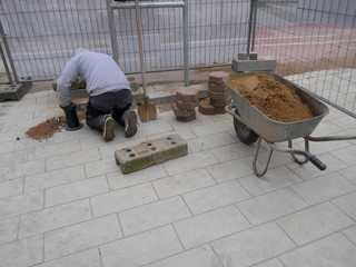 Craftsman  relocates paving stones on a closed construction site