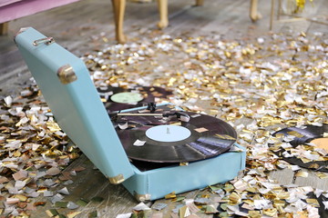 Vintage blue player with vinyl records in a room with golden confetti. New year party time