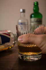 a grabbed glass of whisky and bottles on wooden table