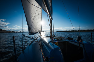 View from the deck to the bow of a sail yacht tilted in a wind on a sunset