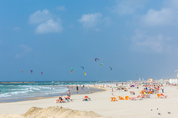 Fototapeta na wymiar Tel Aviv, Israel - Oct 25th 2018 - Big group of people enjoying a sunny day in a beach with many kites in the air in Israel
