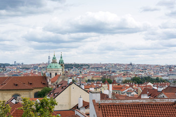 Fototapeta na wymiar Prague panorama with colorful rooftops on a cloudy day, with The Church of St. Nicholas and Zizkov television tower in the distance