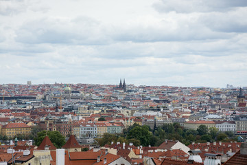 Fototapeta na wymiar Prague panorama with colorful rooftops on a cloudy day, with The Church of St. Ludmila in the distance
