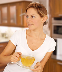 WOMAN IN KITCHEN DRINKING HERBAL TEA