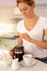 WOMAN IN KITCHEN PREPARING COFFEE
